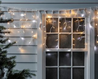 Hanging icicle lights over a window outdoors