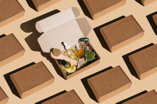 An array of brown parcel packages, with one open in the centre filled with face and body care products.