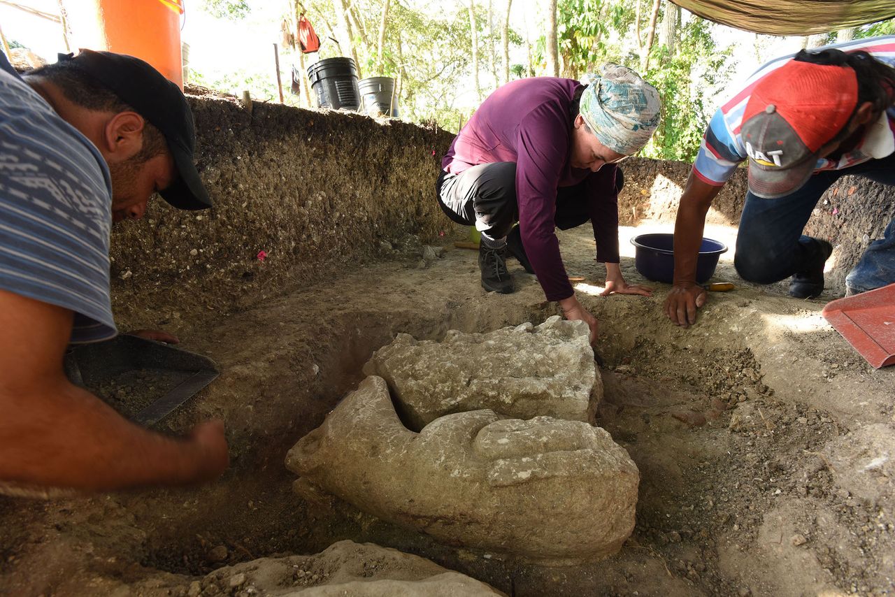 Veronica Vazquez (center) excavates a Middle Preclassic sculpture dating to 1000-700 B.C. on the edge of Aguada F&eacute;nix.
