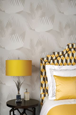 A Geometric II Deco Palm 105-8036 wallpaper from Cole & Son in bedroom with retro yellow and brown headboard and yellow lampshade