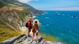 Couple on hiking trip resting on top of the mountain looking at ocean view