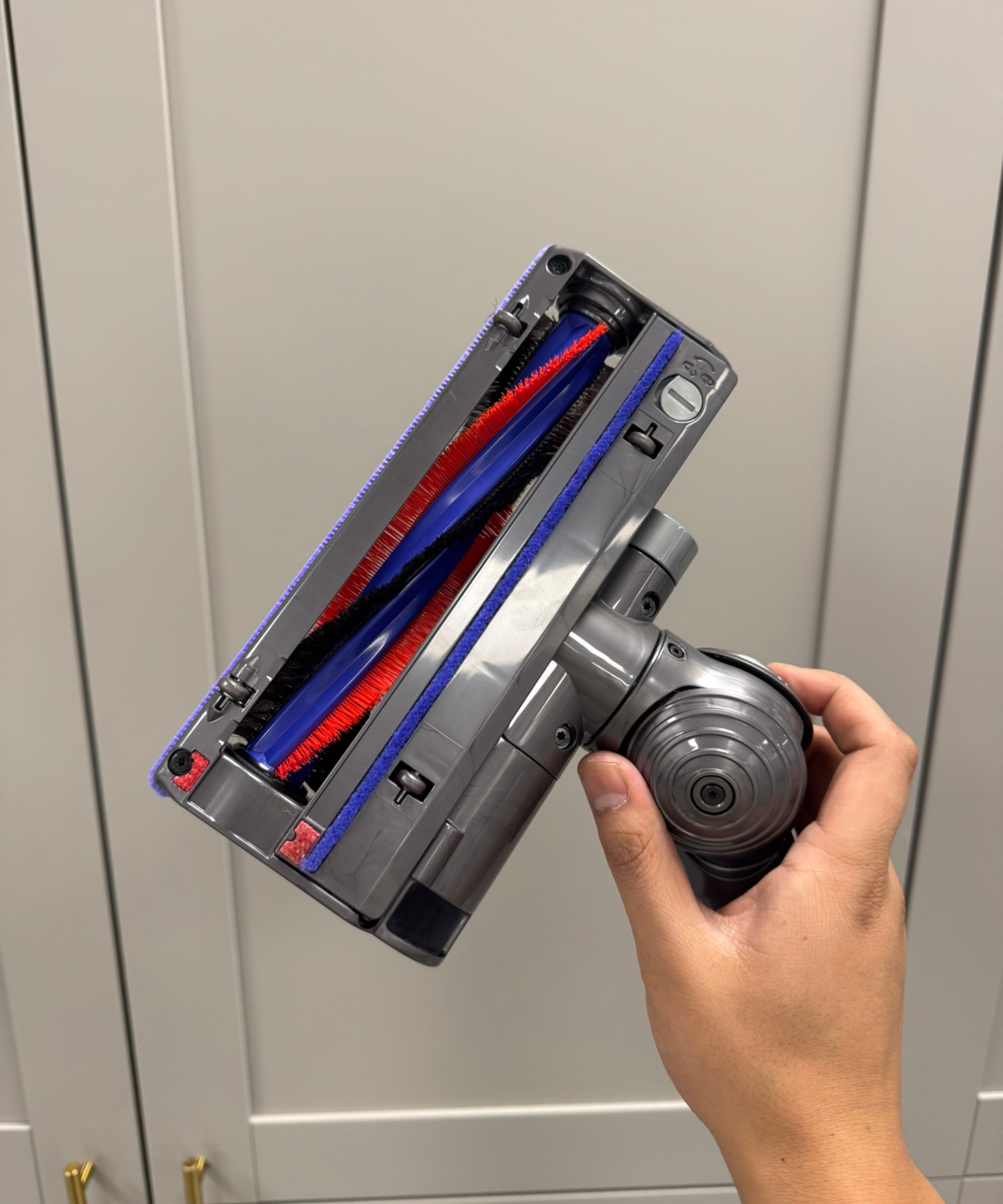 Dyson Big Ball Turbinehead floorhead held by Dan Fauzi's hand in front of gray cabinet doors in Future test center.