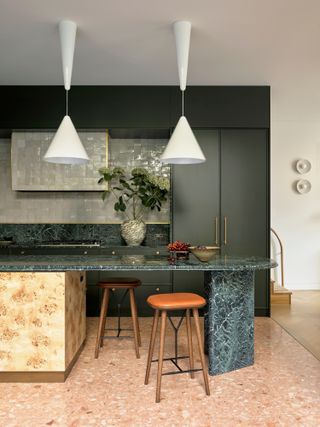 Dark green kitchen with green marble and burled wood island