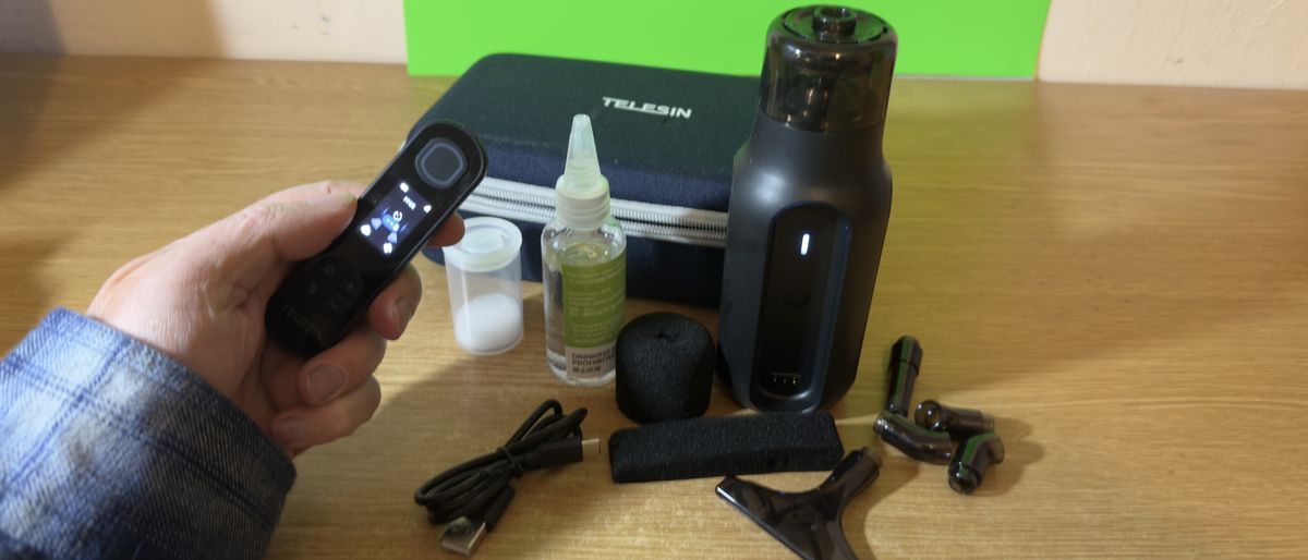 Telesin C40 Portable Smoke Machine kit laid out on a wooden desk with a remote held in a hand