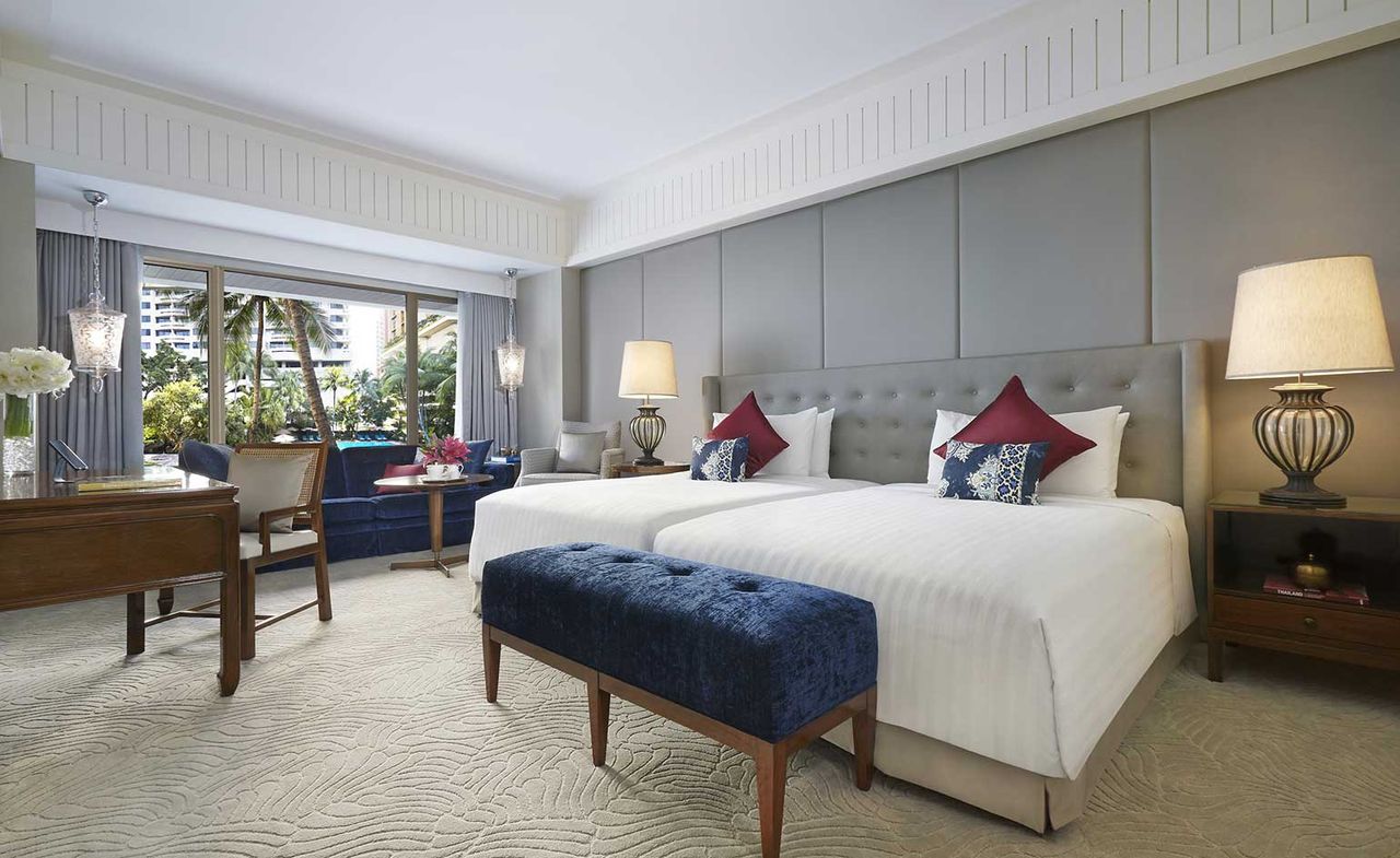 Twin bedroom with soft grey walls, textured carpet and matching stool and sofa