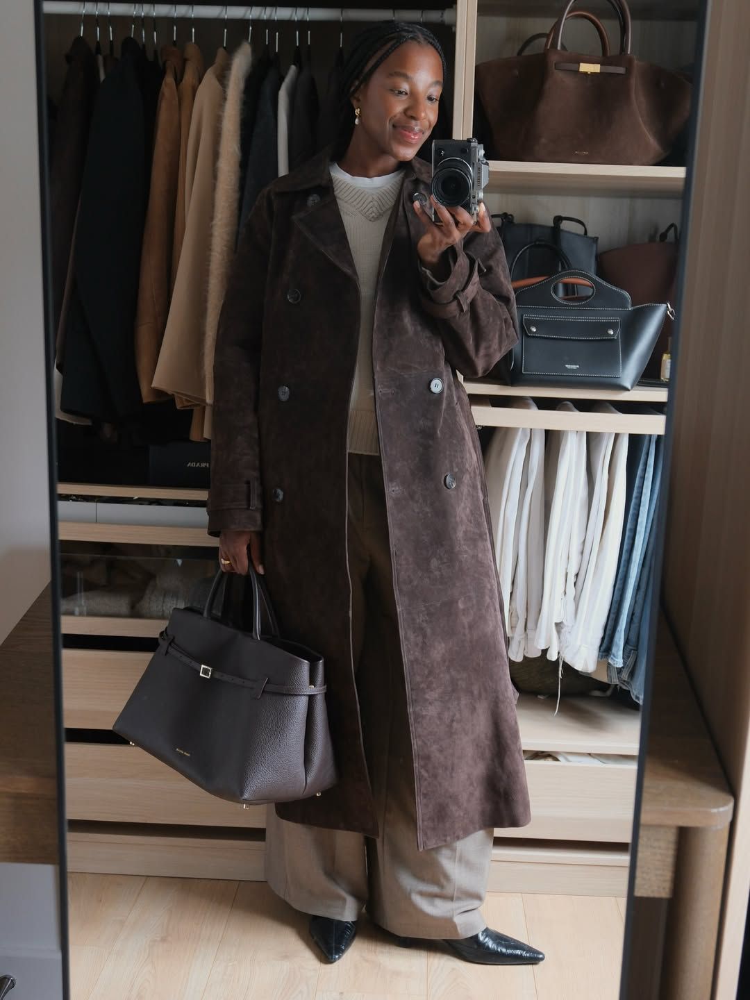Woman wears white T-shirt, beige jumper, brown suede trench coat, brown bag