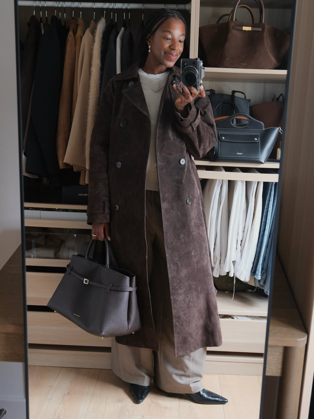 Woman wears white T-shirt, beige jumper, brown suede trench coat, brown bag