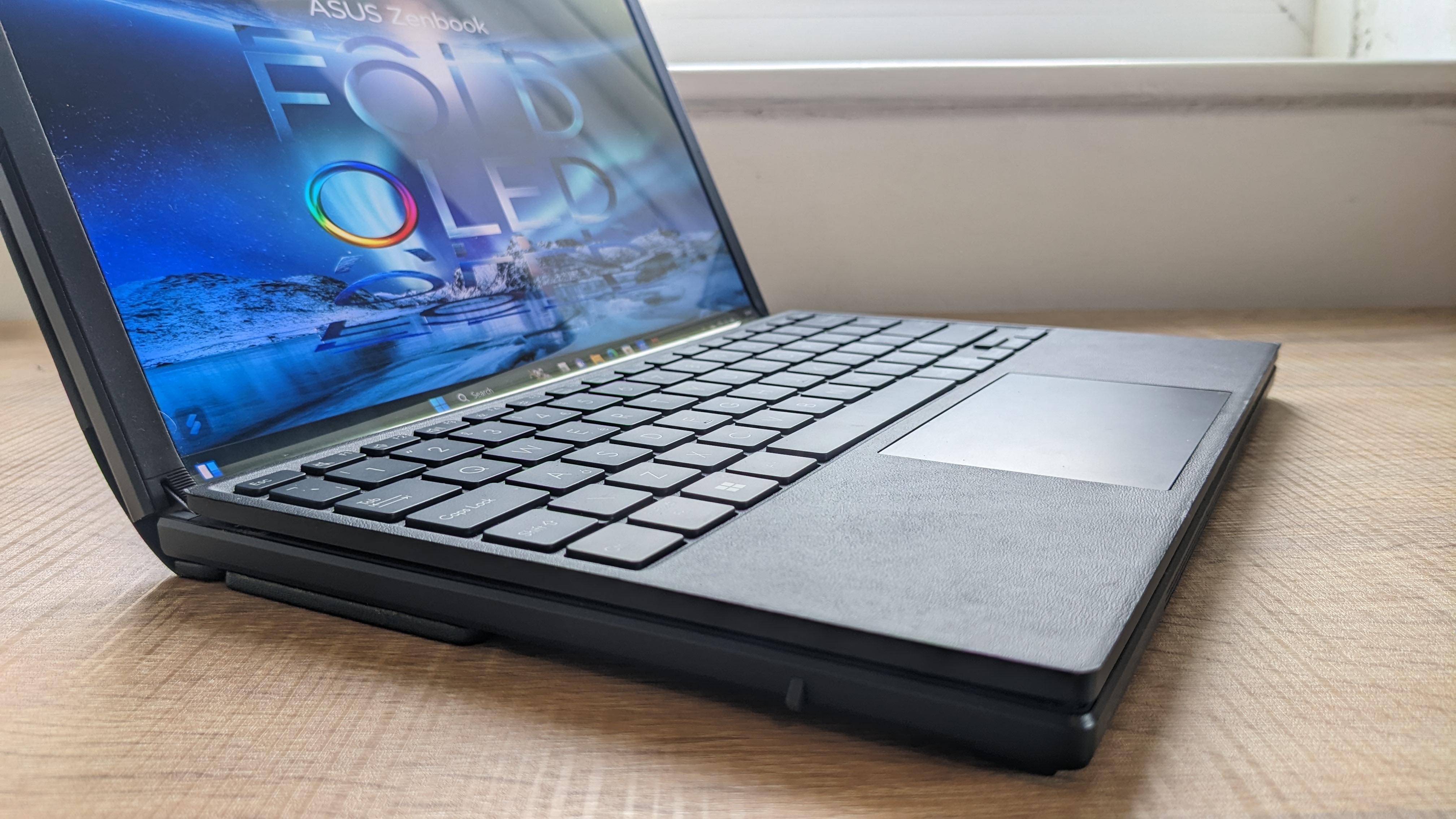 The Asus Zenbook 17 Fold OLED pictured on a wooden desk.