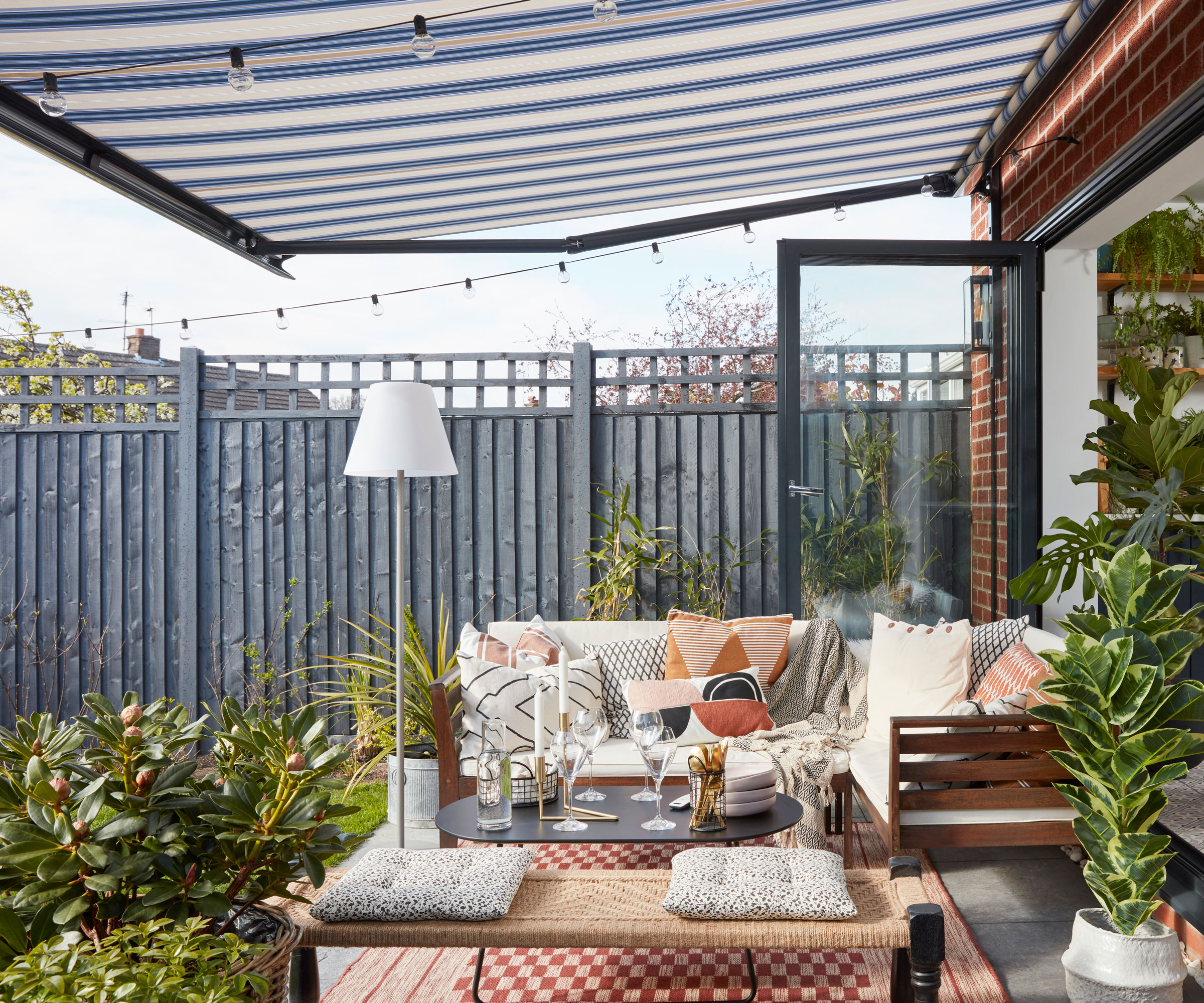 deck area with garden seats, rug and accessories, with stripy blue awning