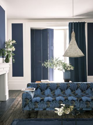 A living room with blue painted doors and blue tufted sofa
