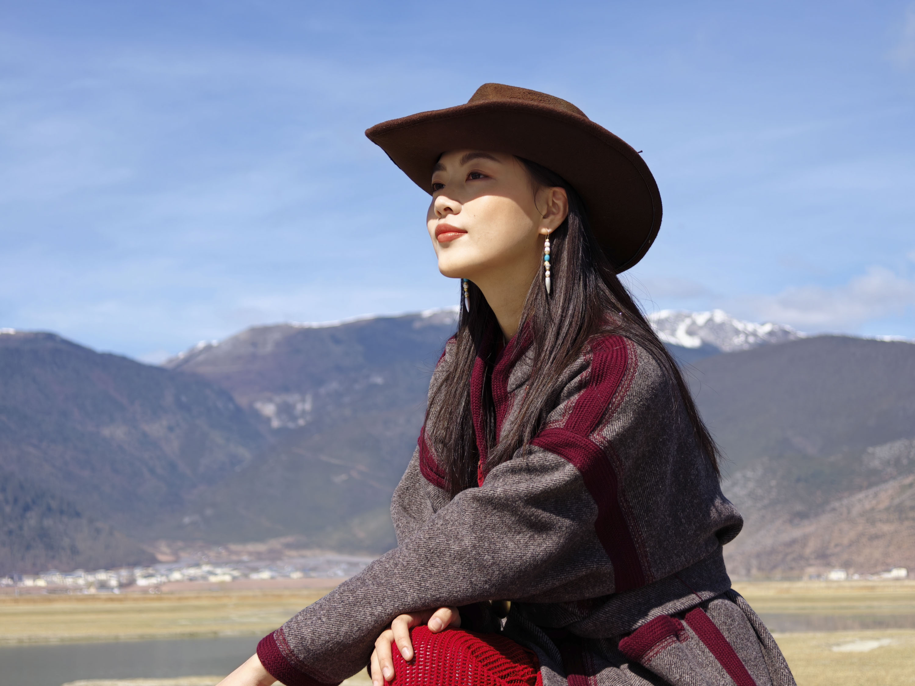A portrait of a woman in a cowboy hat with a snowy mountain backdrop