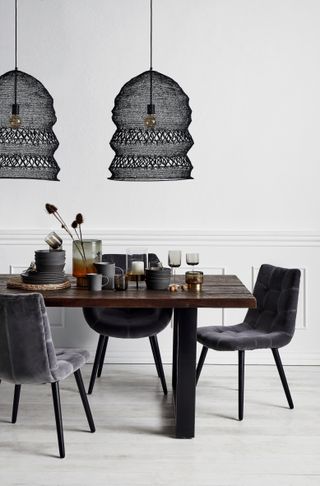 Wire and Thread Pendant Lamp in Black from Out There Interiors over a dining table in a white dining room