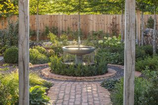 cascade garden fountain in patio with planting and hedging