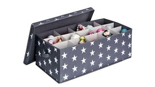 An opened gray Christmas bauble storage box with white star designs and a white cardboard divider tray inside filled with ornaments, for the best ornament storage containers.