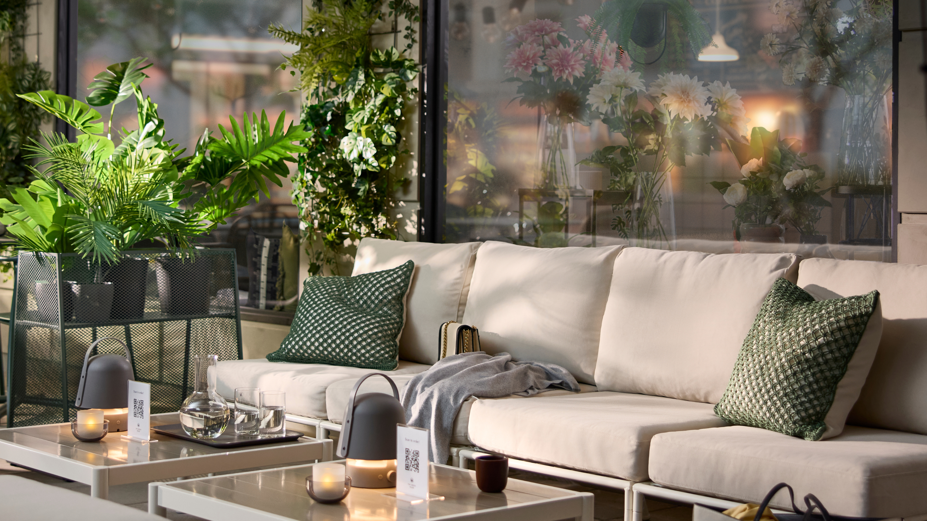 IKEA Plant stand on a patio. There is a large cream garden sofa, coffee table and green cushions.