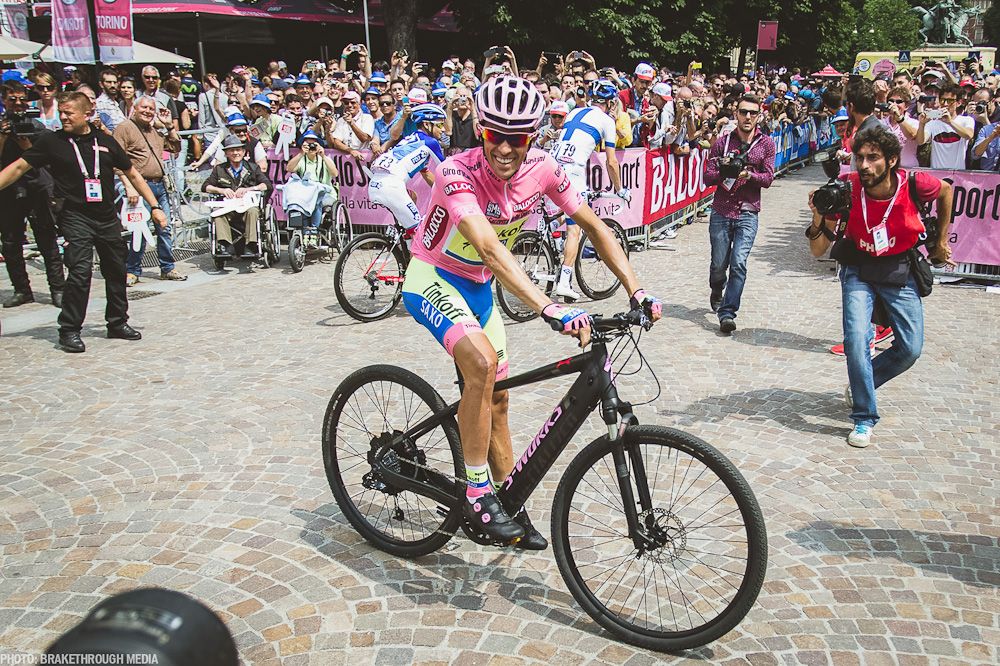 Alberto Contador hops on a different kind of two-wheeler before the start of stage 21.
