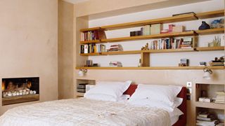 A bedroom with plenty of shelves stacked over the bed