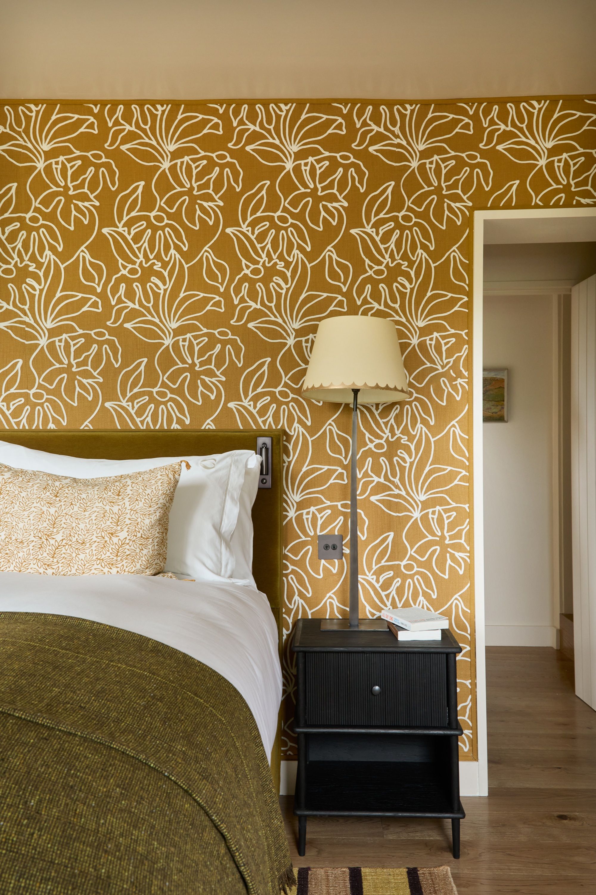 a bedroom with a fabric wallcovering in yellow with white floral pattern
