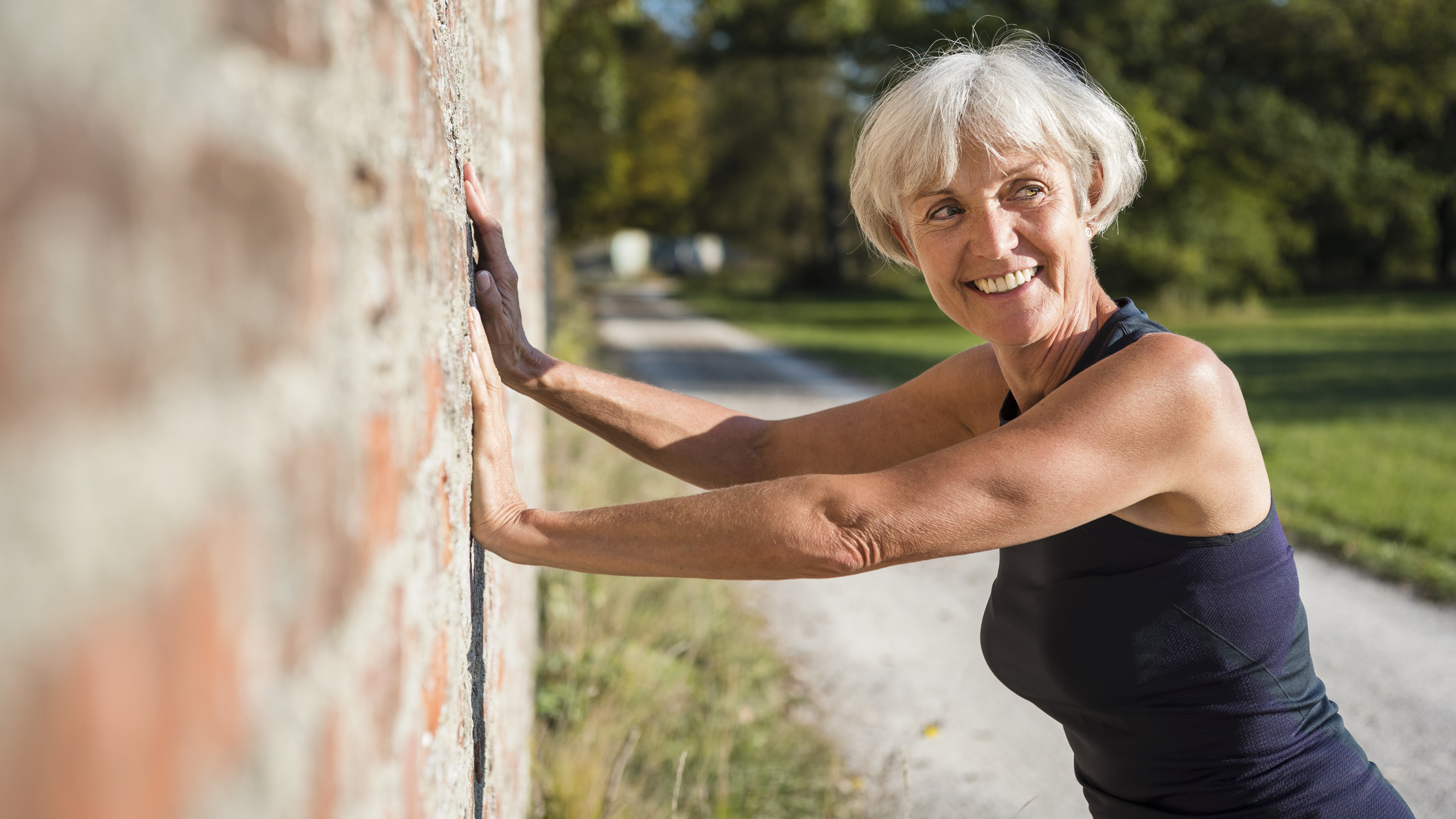 Smiling woman with her hands against a brick wall