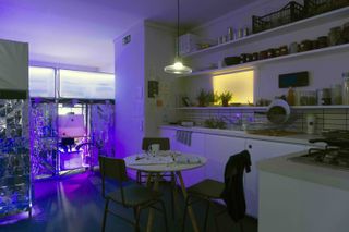 The interior of an apartment showin the setup of the kitchen/dining area with purple lights in the corner