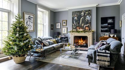Formal living room with Christmas tree and fire lit with grey walls and contemporary artworksash windows