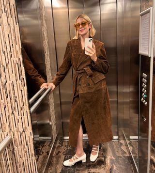 Actress Kelly Rutherford wears Madewell x Alexa Chung brown suede coat and white mary janes while talking elevator selfie.