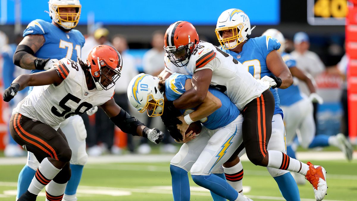 Justin Herbert #10 of the Los Angeles Chargers is sacked by Myles Garrett #95 and Malik McDowell #58 of the Cleveland Browns during the third quarter at SoFi Stadium on Oct. 10, 2021 in Inglewood, California.