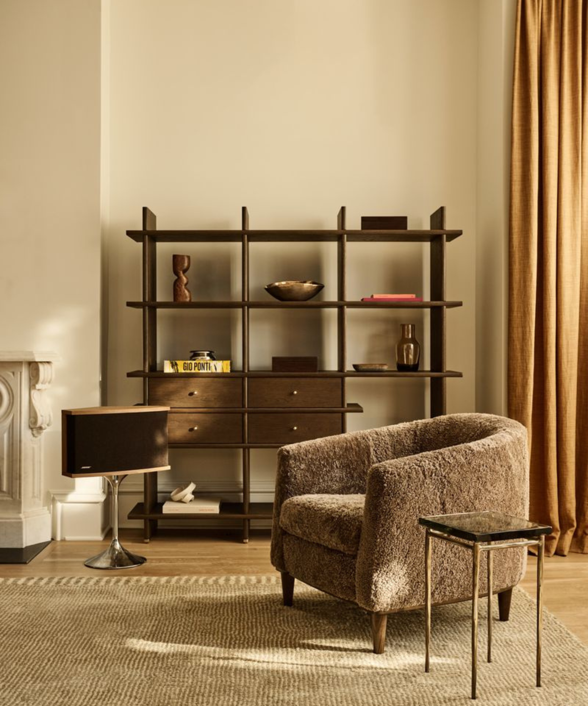 a sitting area with a brown shearling chair, a small side table, and a dark oak bookcase