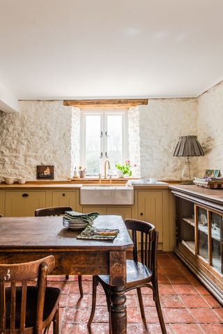 vintage kitchen with white painted brick walls, wooden cabinetry and worktops and a reclaimed shop counter serving as an additional workspace edit58 kitchen by British Standard by Plain English