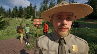 A park ranger near a sign and hikers