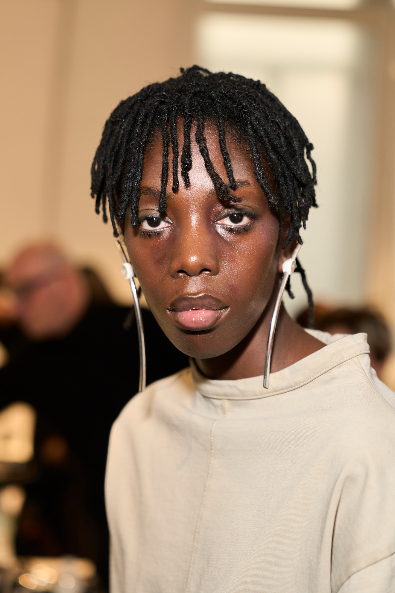 twist bangs on a model with smudged eyeliner and a nude shirt