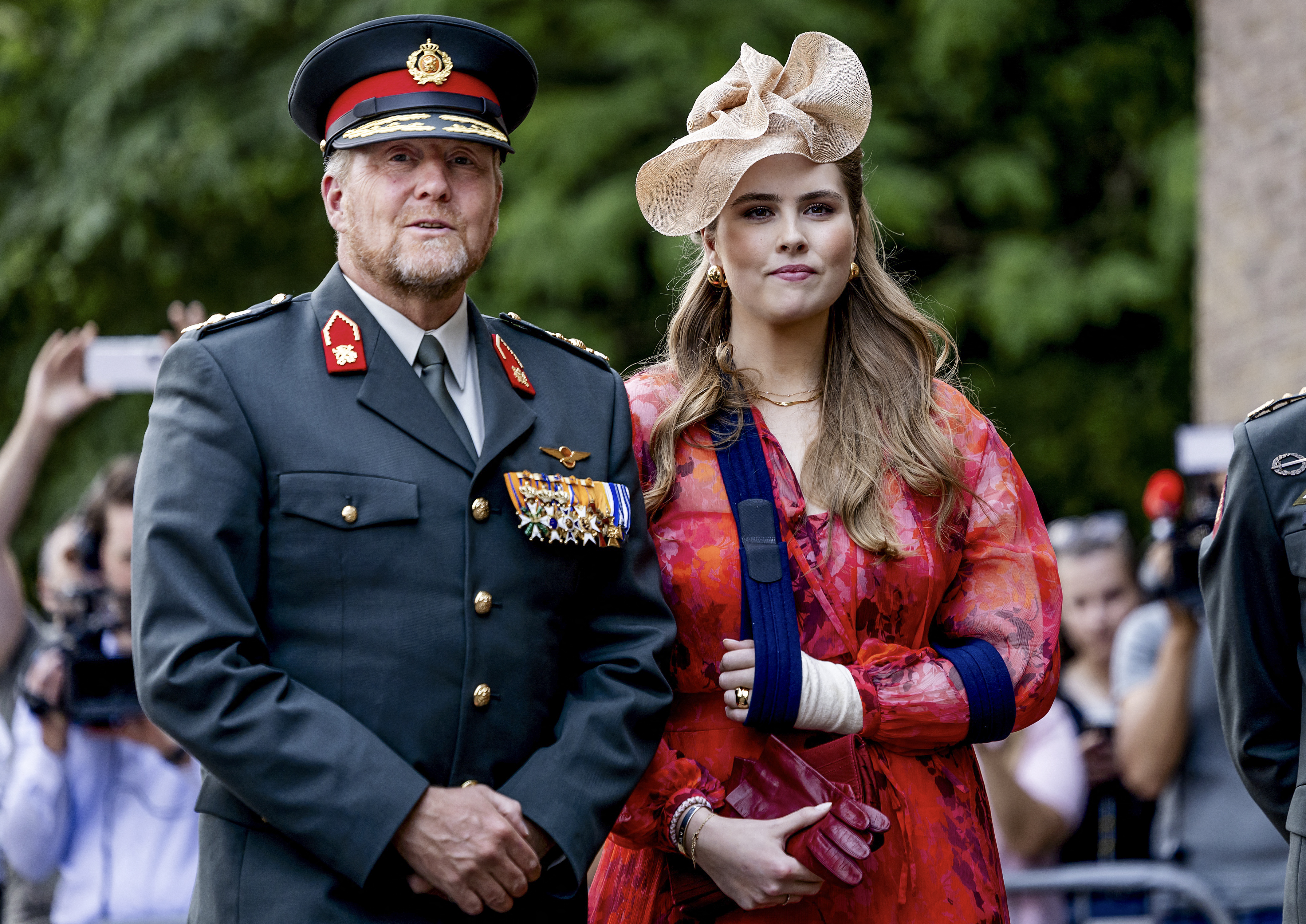 Princess Catharina-Amalia wearing her arm in a sling standing with King Willem-Alexander at a military event
