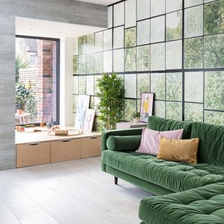 Modern living space with green velvet L-shaped sofa, window-style mural wall and smart grey walls and floors