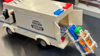 LEGO Joker next to an Arkham Asylum van.