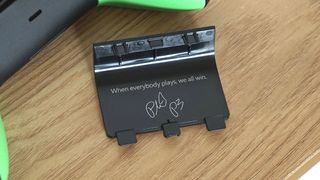 The inside of the battery cover on the Xbox 20th Anniversary controller with the message "when everybody plays, we all win" signed by Phil Spencer.