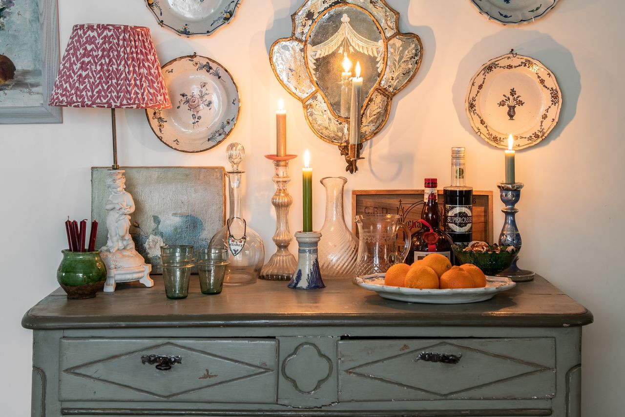 collection of flowered antique plates arranged in a gallery wall around a mirrored candle sconce