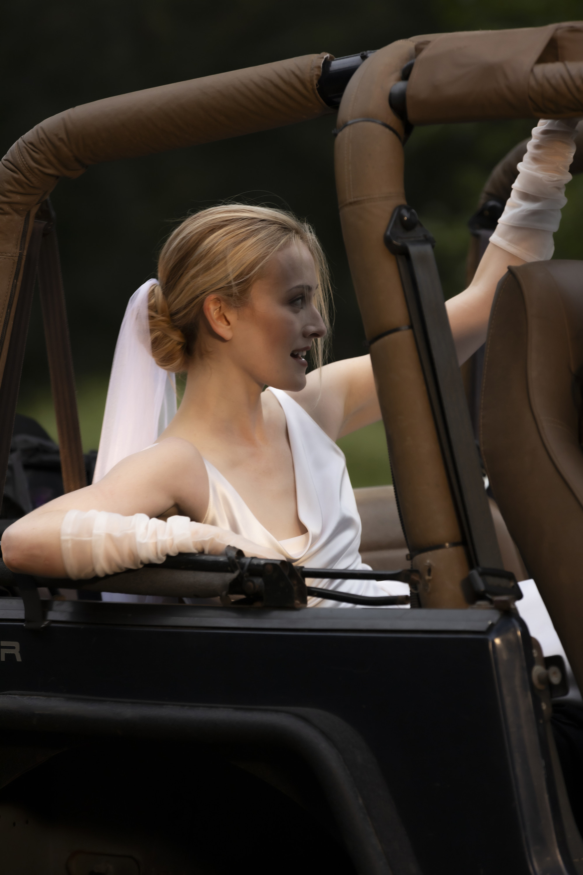 Carolyn Bessette Kennedy riding in a Jeep while wearing her wedding dress