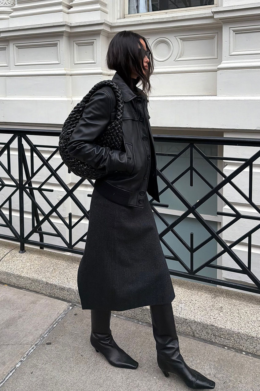 a woman wearing a black leather jacket, black skirt, and black boots