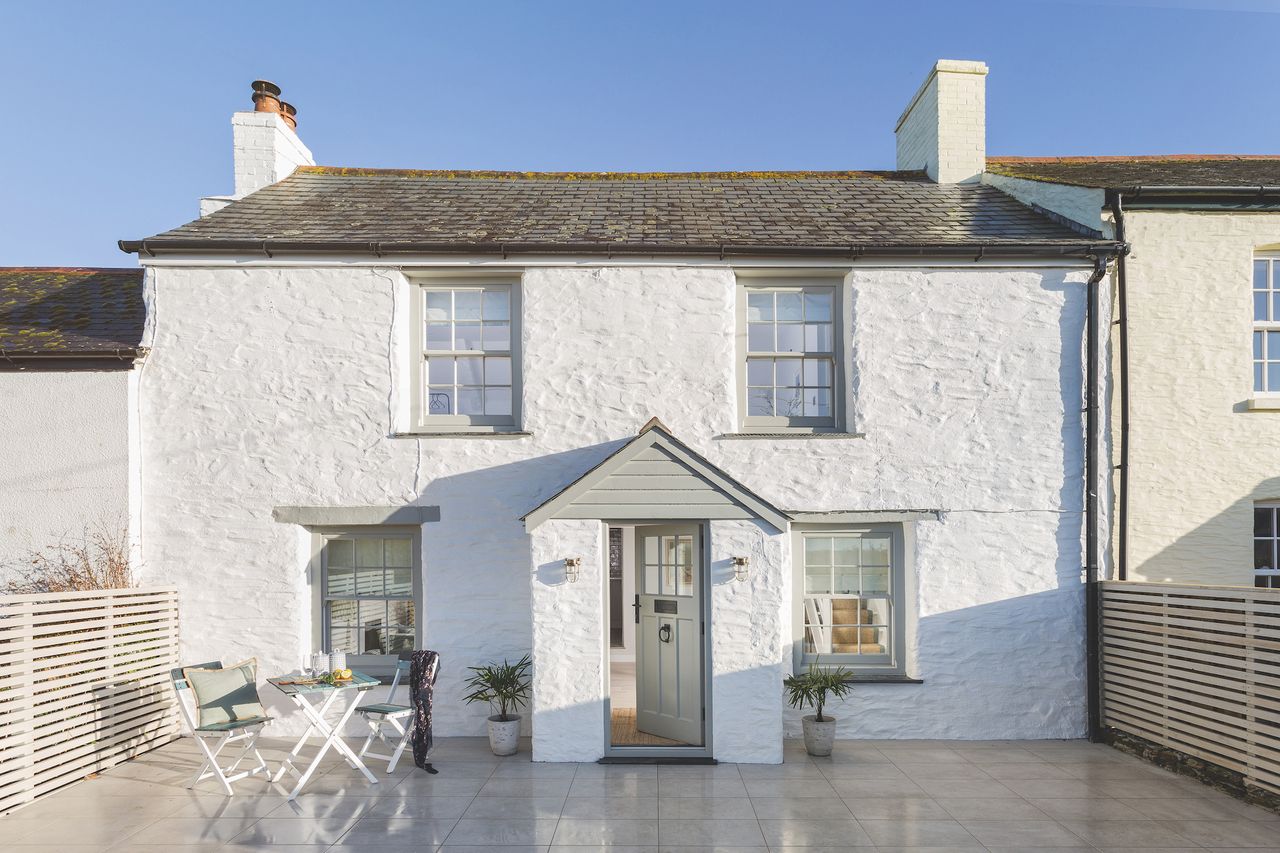 white stone cottage with front porch and patio