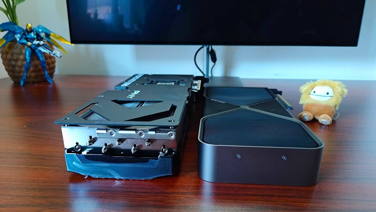 PNY RTX 5080 OC graphics card sitting next to RTX 5080 Founders Edition on woodgrain desk