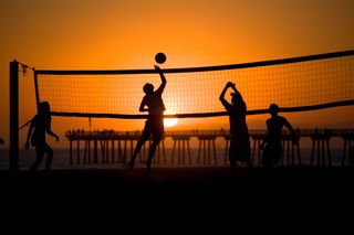 Beach volleyball players play as the sun sets behind them in Hermosa Beach, California