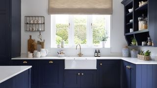 dark blue and white kitchen with butler sink and window