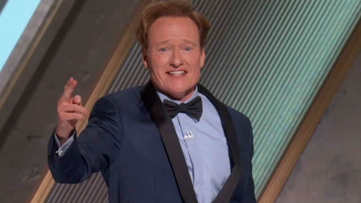 Conan O&#039;Brien smiles in mid salute while wearing a blue tux at the 97th Academy Awards.