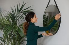 A woman hanging a mirror in her second home