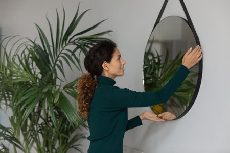A woman hanging a mirror in her second home