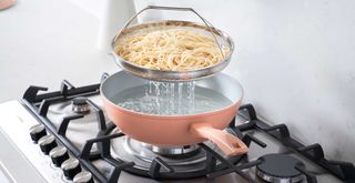 Aldi pan in pink cooking pasta on a stove