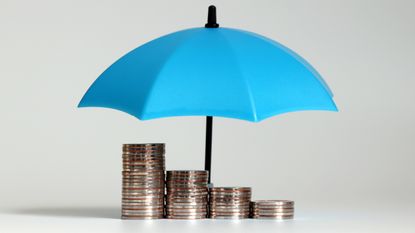 A blue umbrella is opened over stacks of coins at different heights.