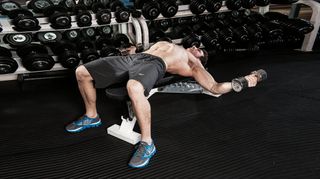 Man does dumbbell flye chest exercise on weight bench