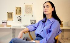 Frida Escobedo sitting in a wooden chair in front of her desk.