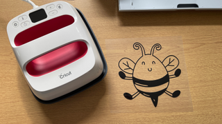 How to use a Cricut; an Easypress 2 heat press on a wooden table with a cute bee design